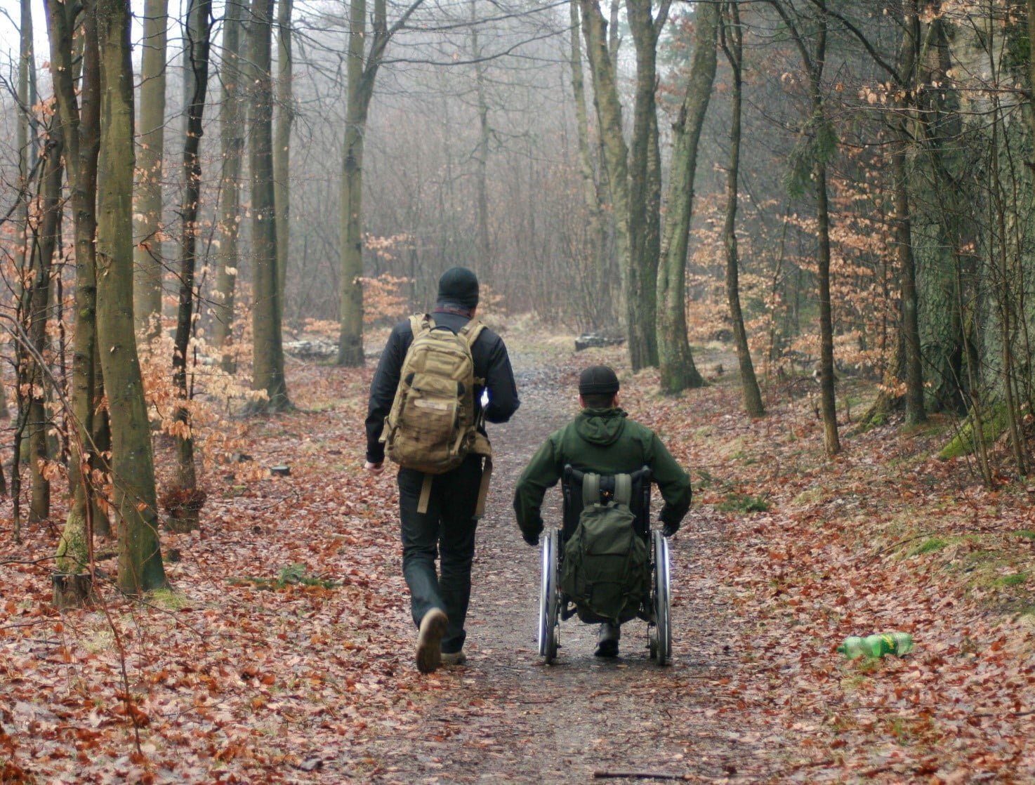 Veteraner med PTSD i naturen set fra ryggen. Den ene er gående. Den anden kører i kørestol.